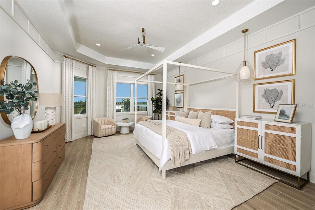 A bright bedroom features a canopy bed, light wood furniture, and a neutral color palette — 17524 MACARTHUR LOOP, VENICE, FL