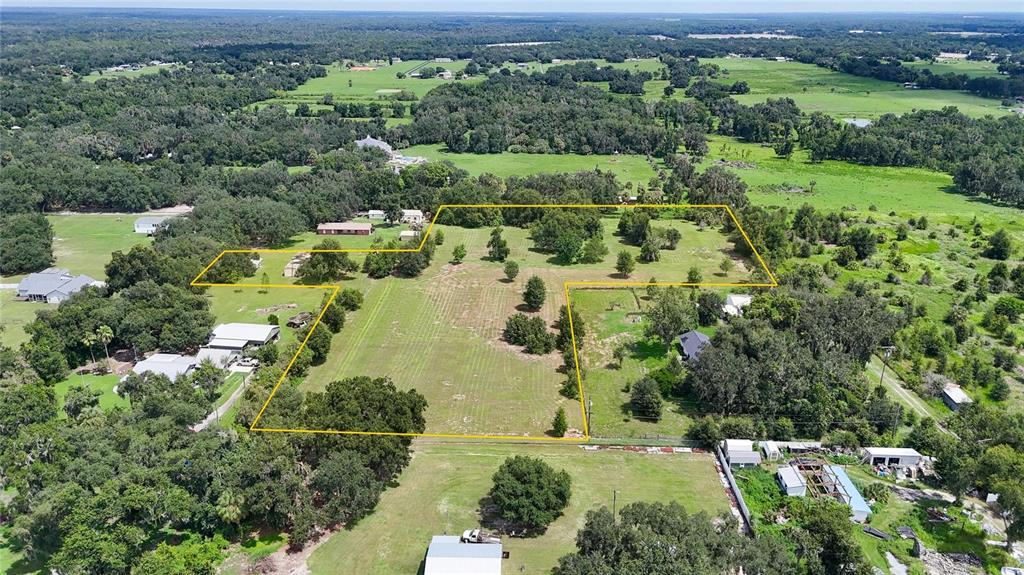 An aerial view shows a large, grassy lot outlined in yellow within a rural landscape — 2452 WELCOME ROAD, LITHIA, FL