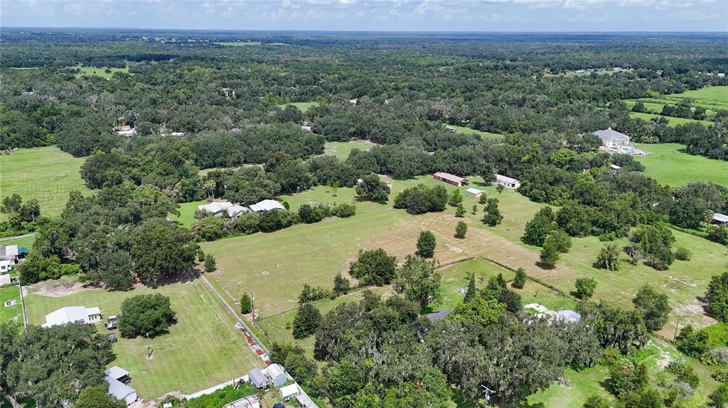 An aerial view shows a large, grassy rural property with scattered trees and several buildings — 2452 WELCOME ROAD, LITHIA, FL