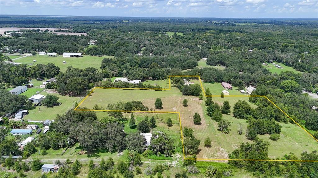 An aerial view shows a large, grassy rural property outlined in yellow with scattered trees — 2452 WELCOME ROAD, LITHIA, FL