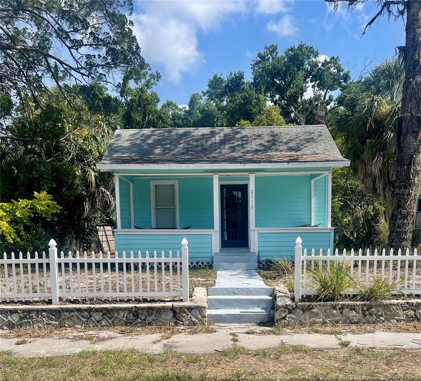 A living room features a floral sofa, wooden trunk coffee table, and a glass-paneled door — 2513 8TH AVENUE W, BRADENTON, FL