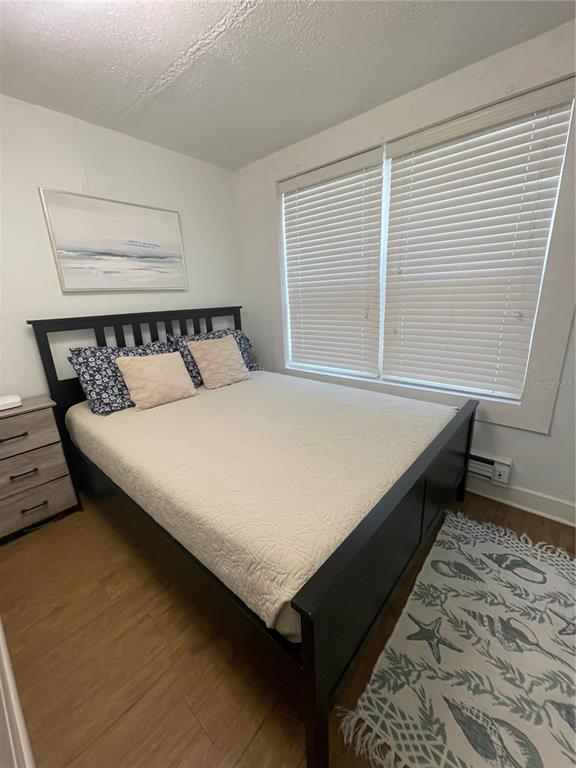 A bedroom features a white bed, a wooden dresser, built-in shelving, and a doorway — 2513 8TH AVENUE W, BRADENTON, FL