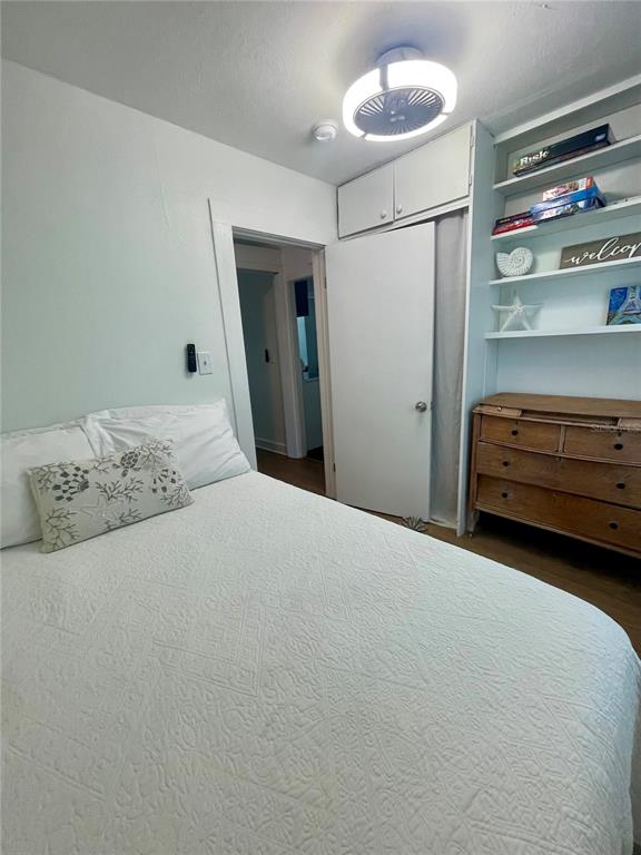 A bedroom features a bed with a white textured quilt, patterned pillows, and a side table — 2513 8TH AVENUE W, BRADENTON, FL