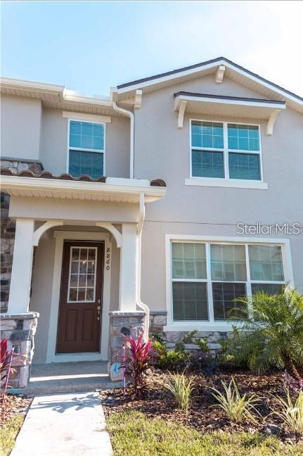 The exterior of a two-story house features a brown front door and stone accents — 8860 HERENCIA ALLEY, WINDERMERE, FL