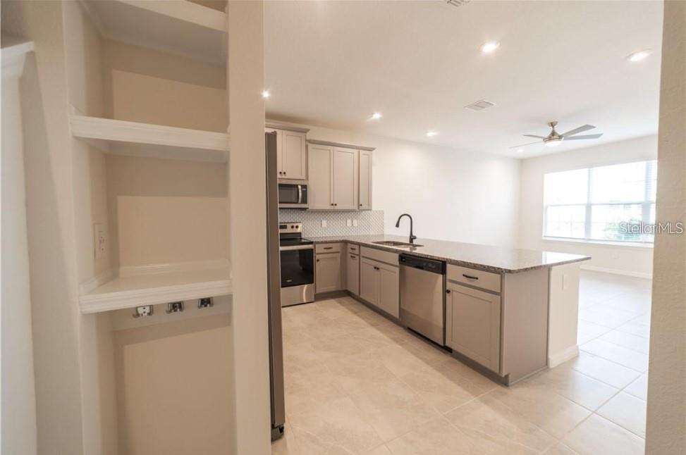 A kitchen features light gray cabinets, stainless steel appliances, and a granite-topped island — 8860 HERENCIA ALLEY, WINDERMERE, FL
