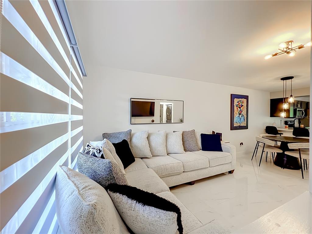 A living room features a white sectional sofa, tiled floors, and an adjacent dining area — 121 RESERVE CIRCLE UNIT 105, OVIEDO, FL