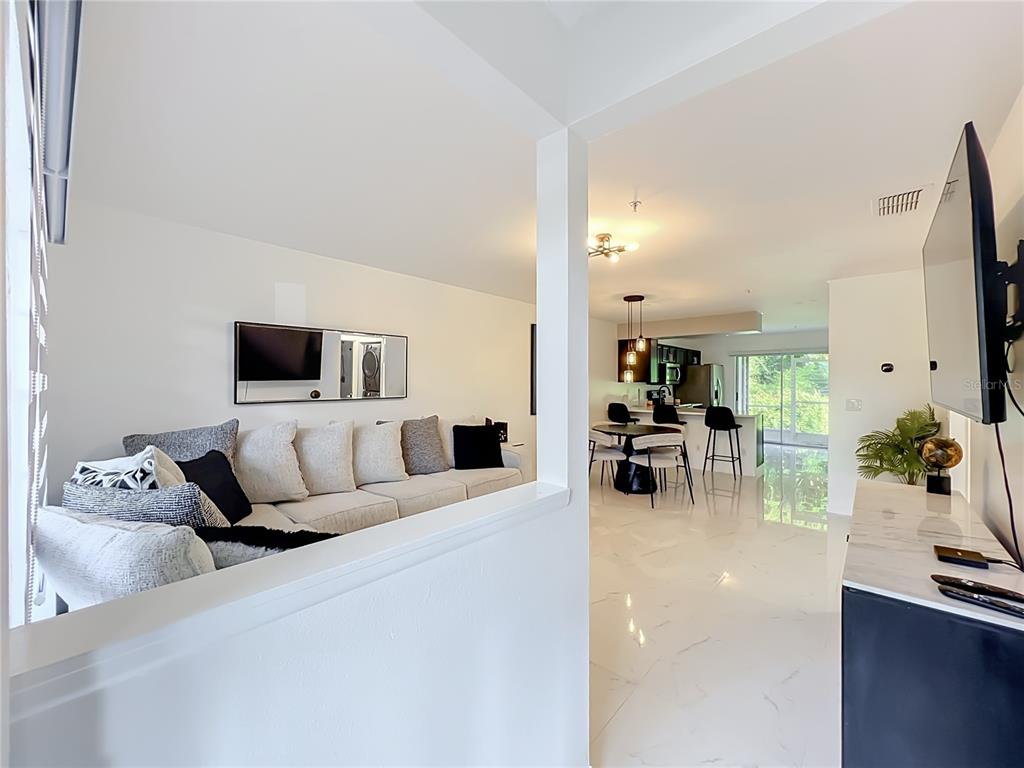 A living room with a white sofa opens to a dining area and kitchen beyond — 121 RESERVE CIRCLE UNIT 105, OVIEDO, FL