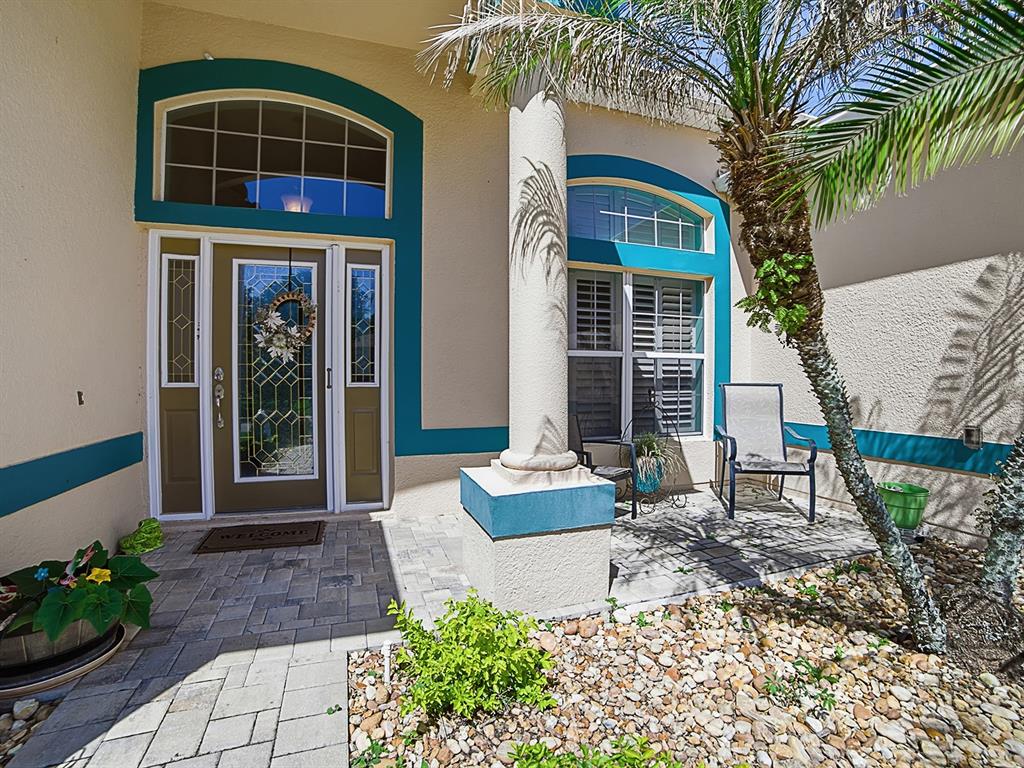 The front entrance of a house features a paved walkway, a column, and teal trim — 24511 BOCAGE WAY, LEESBURG, FL