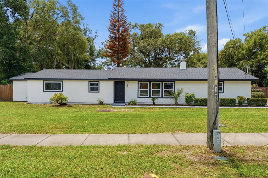 A single-story white house with a dark roof and black trim sits behind a lawn — 147 COLOMBA ROAD, DEBARY, FL