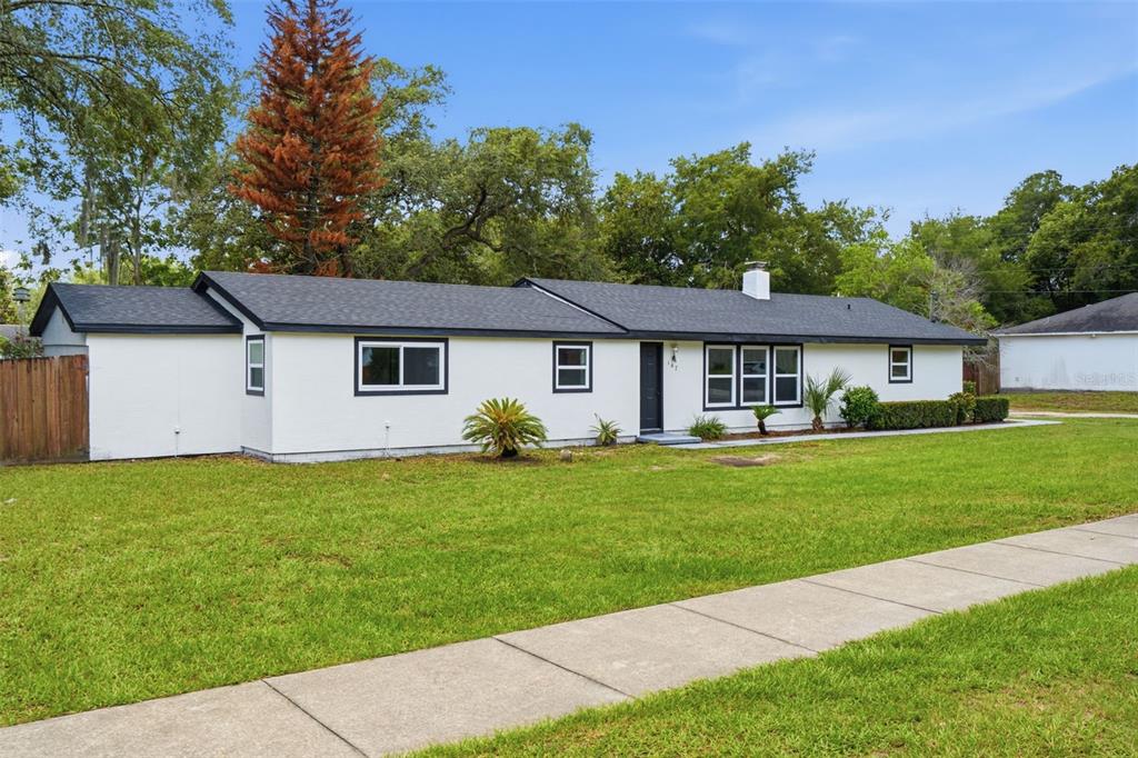 A single-story white house with a dark roof and black trim sits on a lawn — 147 COLOMBA ROAD, DEBARY, FL