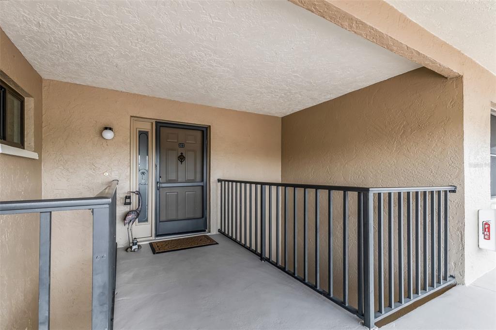 An exterior view of a residential apartment entrance with a dark door and metal railing — 240 LEWIS CIRCLE UNIT 23, PUNTA GORDA, FL