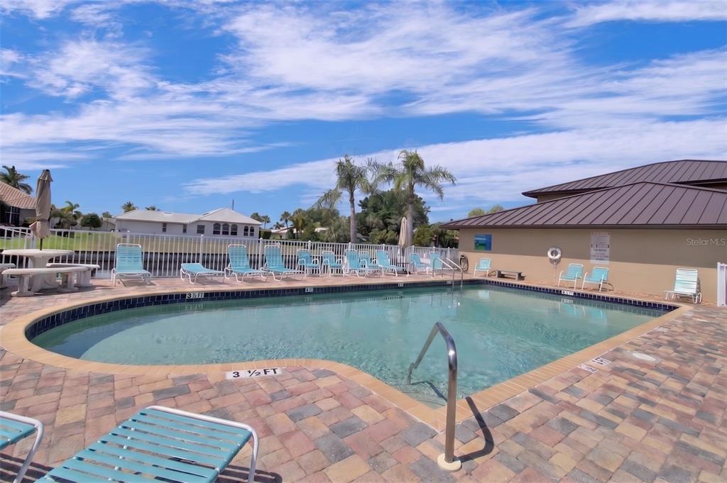 A swimming pool with lounge chairs on a paved deck under a blue sky — 240 LEWIS CIRCLE UNIT 23, PUNTA GORDA, FL