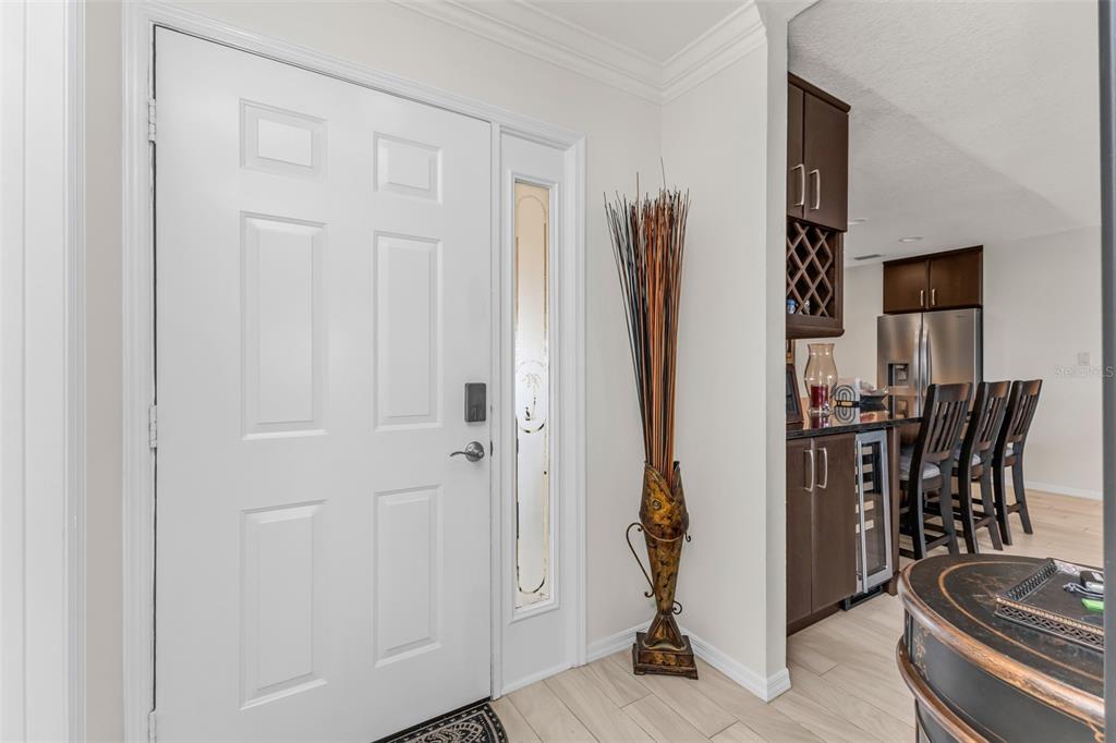 A white front door with a side light opens into a home with wood-look flooring — 240 LEWIS CIRCLE UNIT 23, PUNTA GORDA, FL