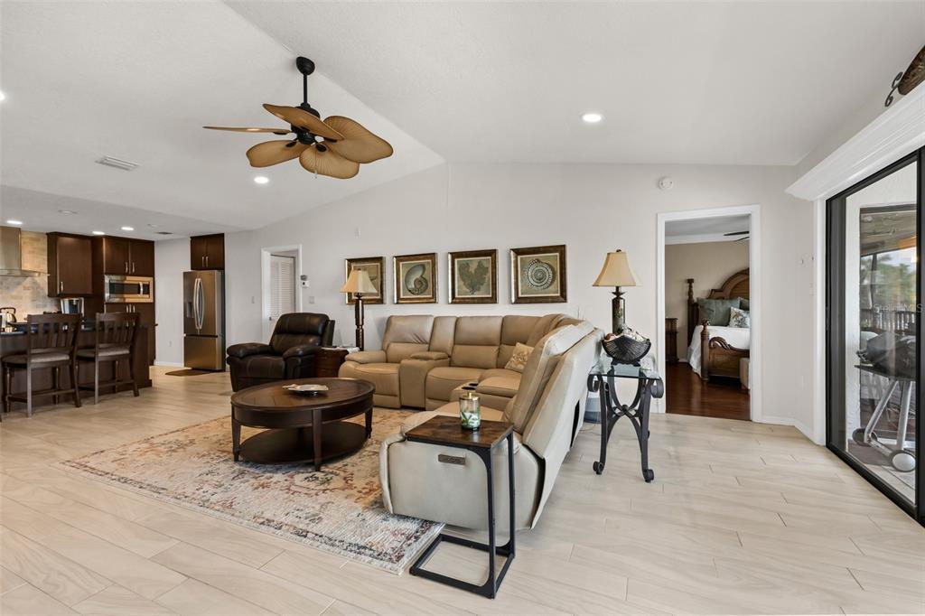 A living room with a beige sectional, dark wood coffee table, and open kitchen area — 240 LEWIS CIRCLE UNIT 23, PUNTA GORDA, FL