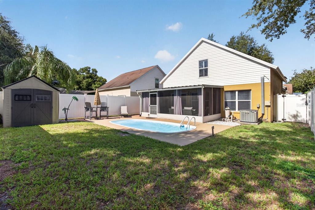 A backyard features a small swimming pool, a screened-in patio, and a storage shed — 1742 HORSECHESTNUT COURT, NEW PORT RICHEY, FL
