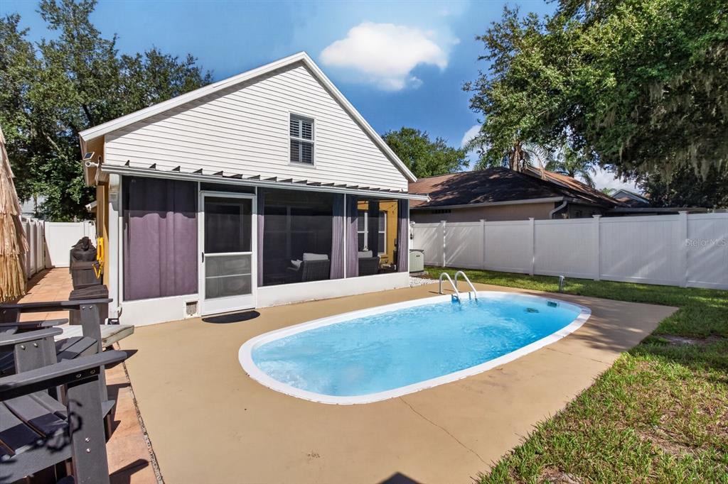 A backyard features a swimming pool, a screened-in patio, and a white vinyl privacy fence — 1742 HORSECHESTNUT COURT, NEW PORT RICHEY, FL