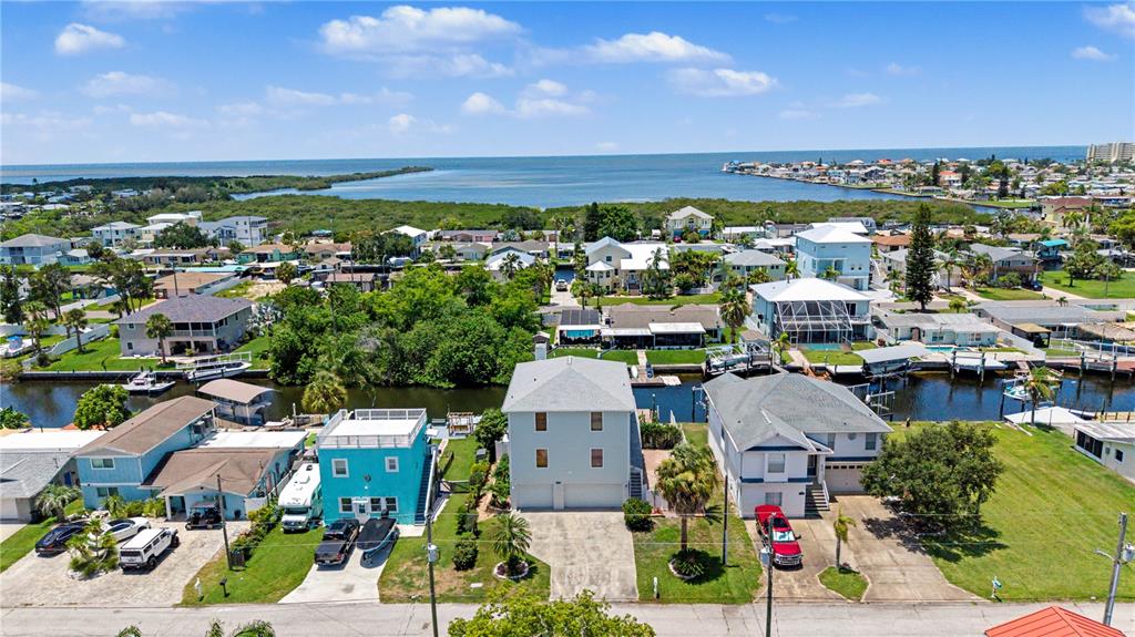 An aerial view shows several waterfront houses with docks along a canal near the ocean — 13337 SUSAN DRIVE, HUDSON, FL
