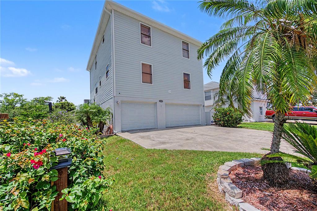 A three-story house with light siding, two garage doors, and a palm tree in front — 13337 SUSAN DRIVE, HUDSON, FL