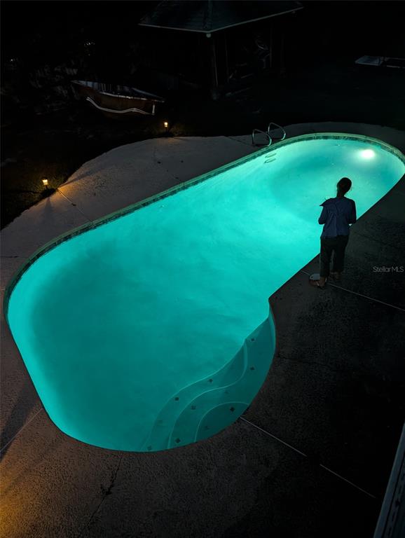 A two-story house at night with a glowing blue swimming pool and an illuminated deck — 6817 MITCHELL CIRCLE, TAMPA, FL
