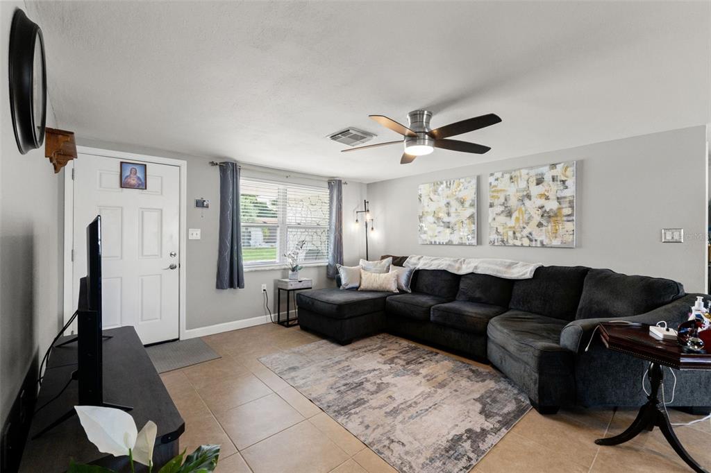 A living room features a dark sectional sofa, tile flooring, and a ceiling fan — 9135 HERMITAGE LANE, PORT RICHEY, FL
