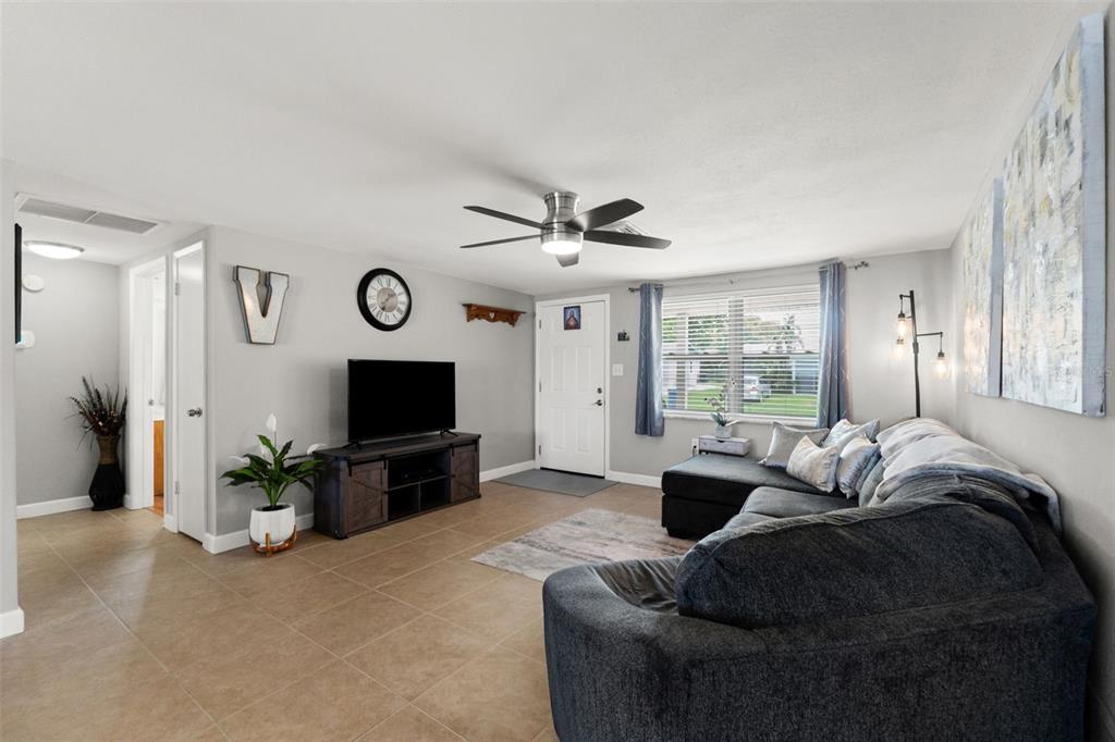 A living room features light tile floors, a gray sectional sofa, and a ceiling fan — 9135 HERMITAGE LANE, PORT RICHEY, FL