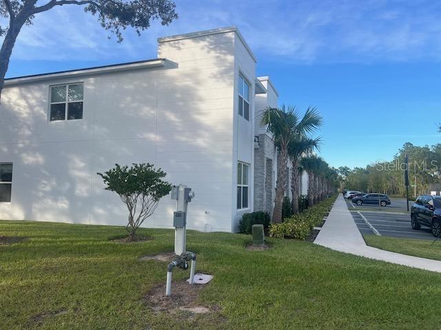 A two-story white building with a stone accent wall and a sidewalk along a parking lot — 1411 SERENDIPITY LANE, CLERMONT, FL