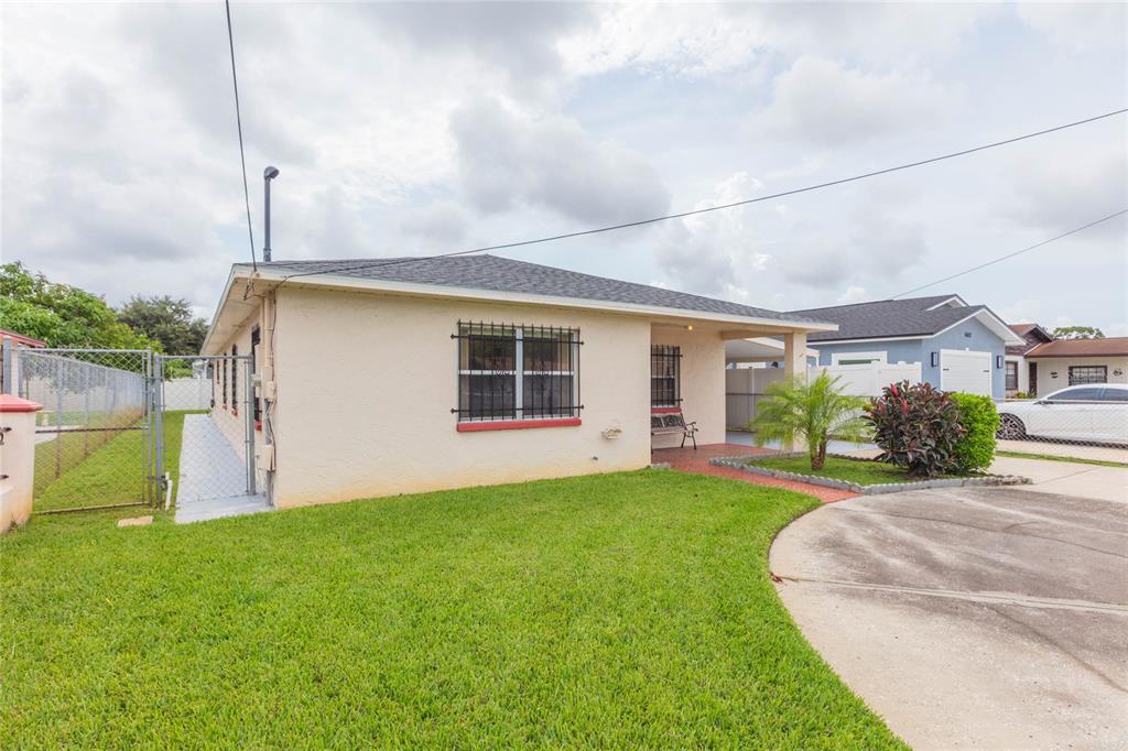 A single-story house with a beige stucco exterior, a front porch, and a grassy yard — 6611 N CLARK AVENUE, TAMPA, FL