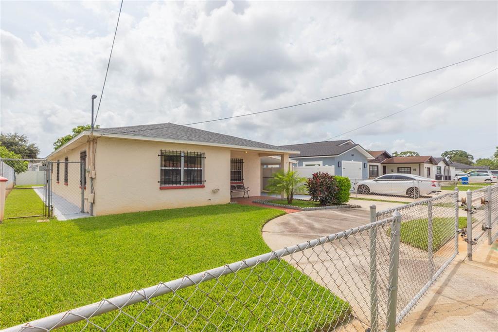 A single-story house with a beige exterior, a front lawn, and a chain-link fence — 6611 N CLARK AVENUE, TAMPA, FL