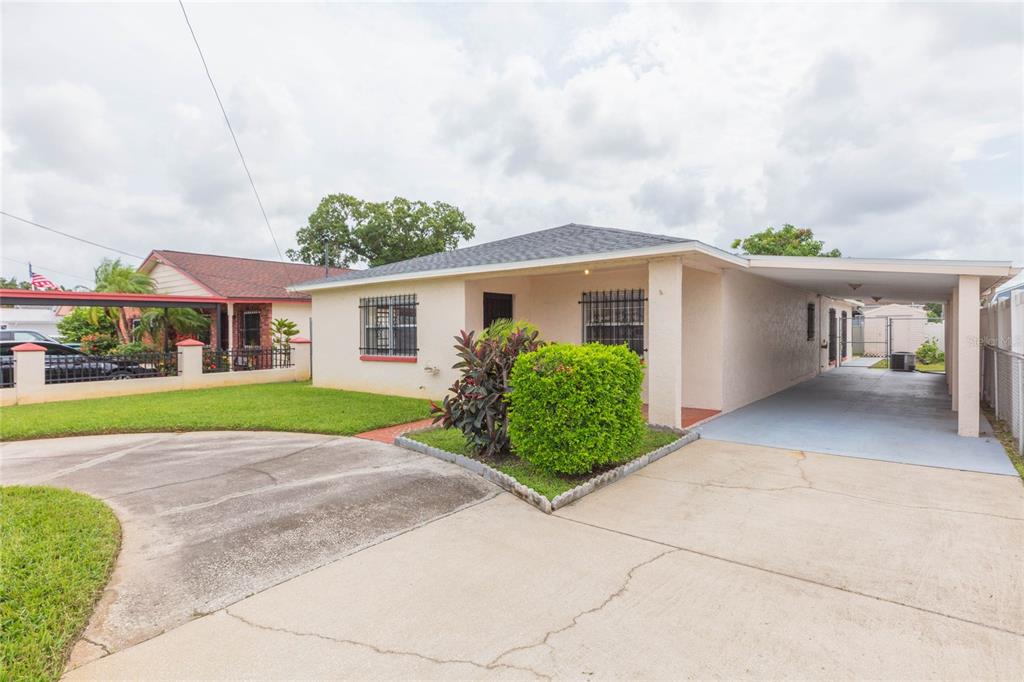A single-story house with a concrete driveway, a carport, and a small front yard — 6611 N CLARK AVENUE, TAMPA, FL