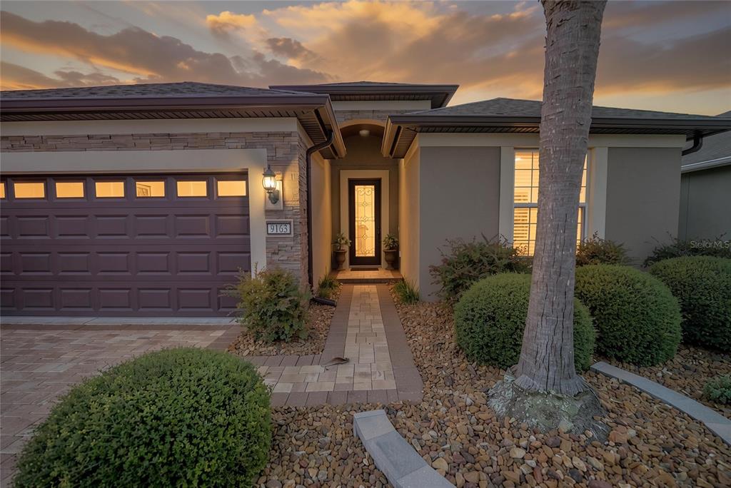A single-story house exterior features a stone facade, a dark garage door, and a walkway — 9163 SW 70TH LOOP, OCALA, FL