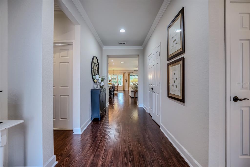 A hallway with dark wood flooring leads to an open living area with white walls — 9163 SW 70TH LOOP, OCALA, FL