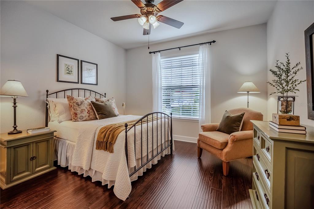 A bedroom features a metal bed frame, a tan armchair, and dark wood flooring — 9163 SW 70TH LOOP, OCALA, FL