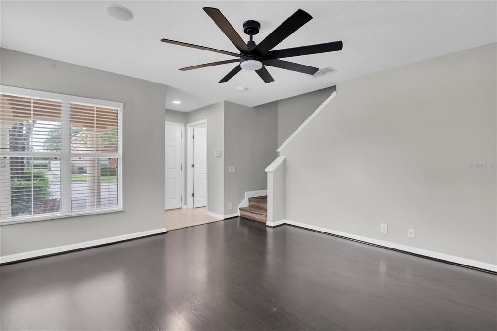 A living room features dark hardwood floors, light gray walls, and a large ceiling fan — 2570 SEA WIND WAY, CLEARWATER, FL