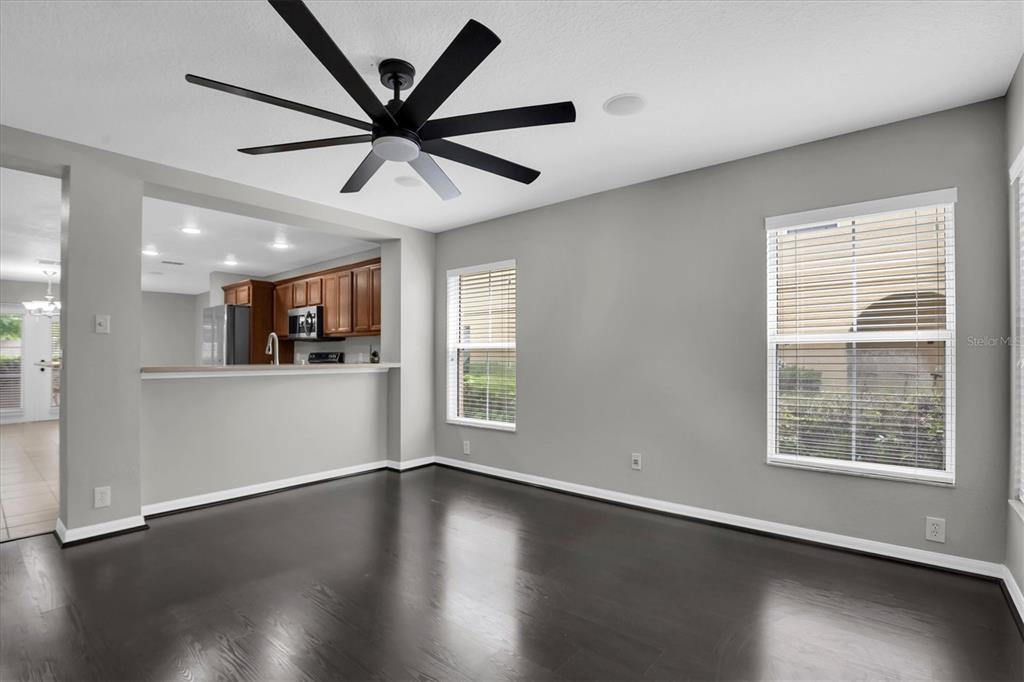 A dining room with dark wood floors, gray walls, a ceiling fan, and two windows — 2570 SEA WIND WAY, CLEARWATER, FL