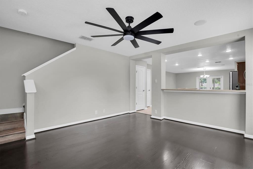 An empty room features dark wood flooring, light gray walls, and a large black ceiling fan — 2570 SEA WIND WAY, CLEARWATER, FL