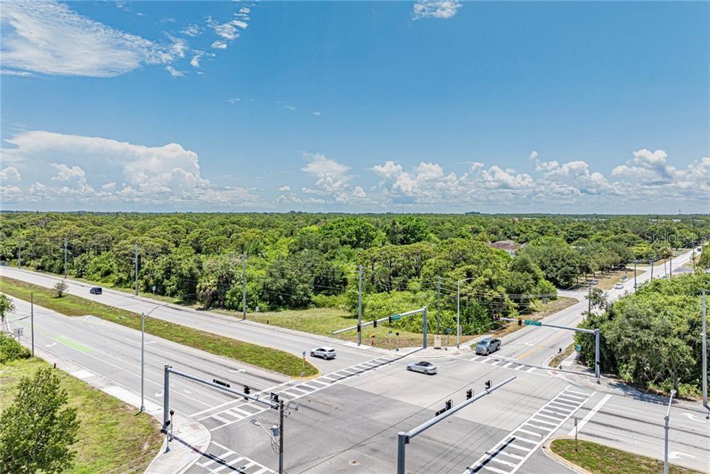 An aerial view shows a paved intersection surrounded by dense green trees and a blue sky — 2551 ST LUCIE BOULEVARD, FORT PIERCE, FL