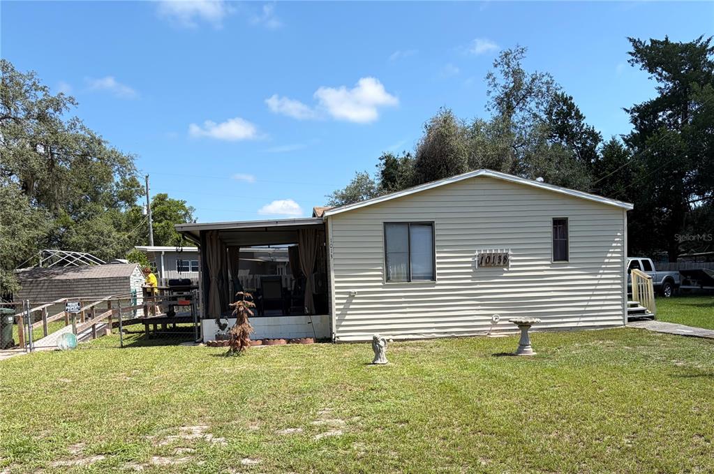 A light-colored single-story house with a screened-in porch and a grassy yard — 10138 E BASS CIRCLE, INVERNESS, FL