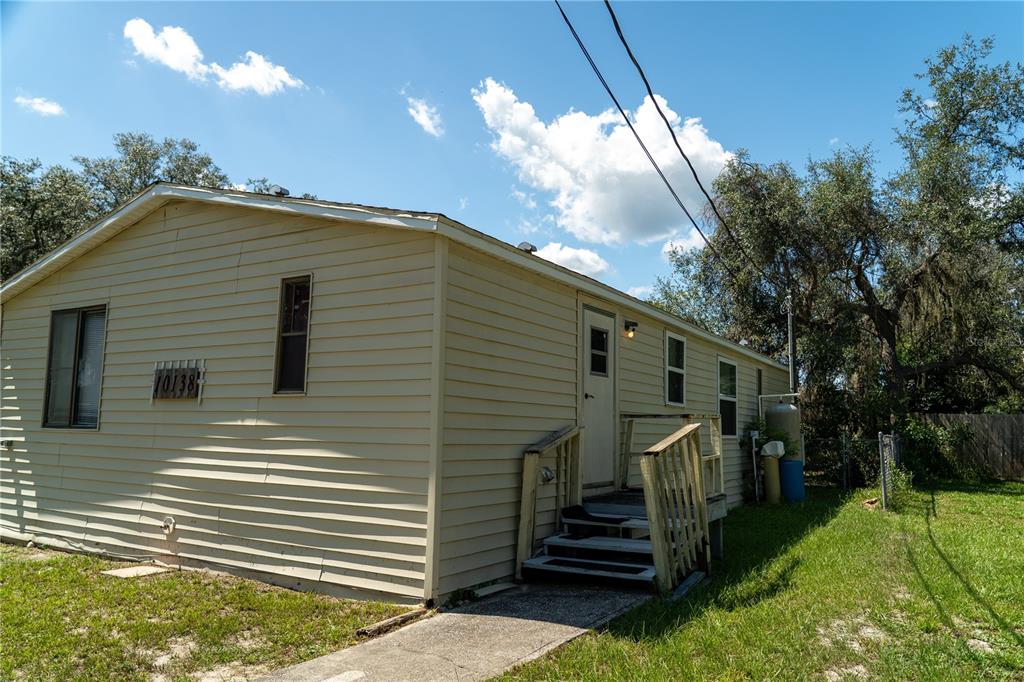 A single-story house with beige siding, a small wooden staircase, and a concrete walkway — 10138 E BASS CIRCLE, INVERNESS, FL