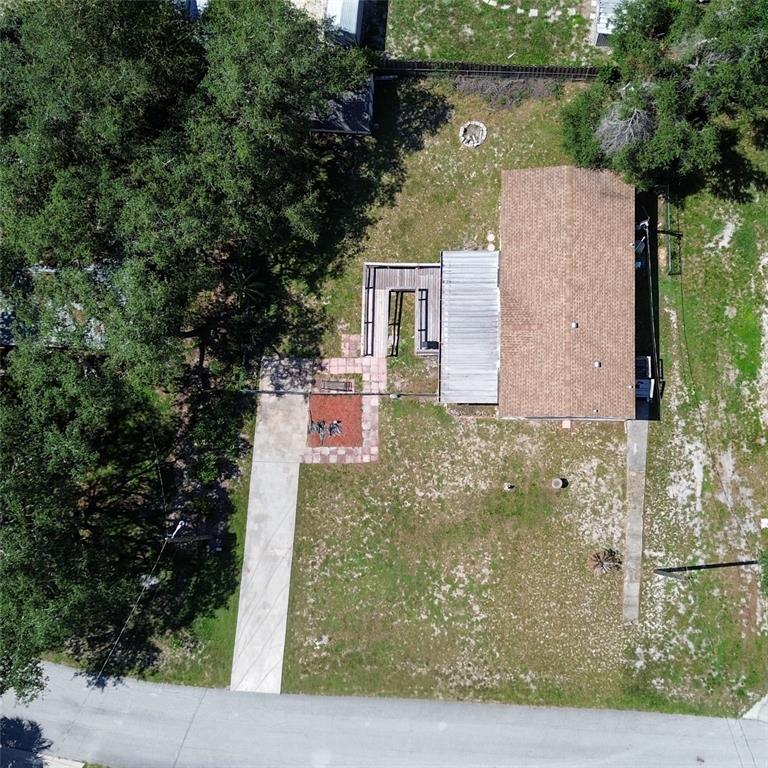 An aerial view shows a house with a shingled roof, deck, and concrete driveway — 10138 E BASS CIRCLE, INVERNESS, FL