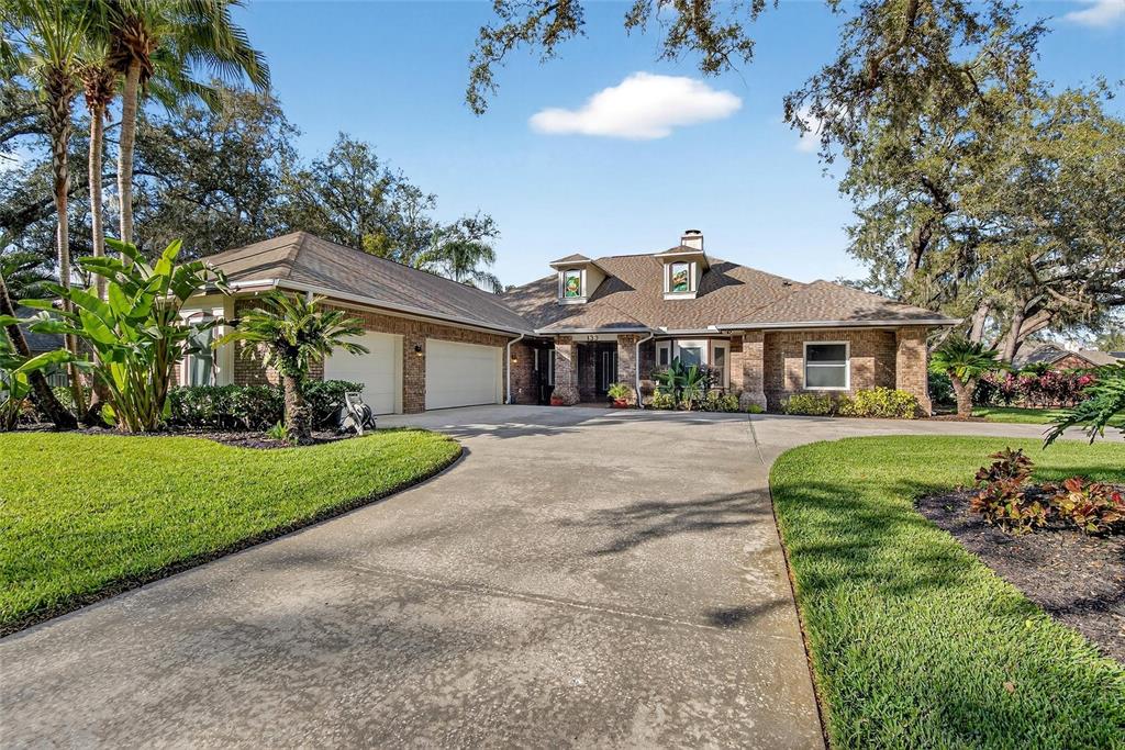 A single-story brick house features a large concrete driveway, a garage, and dormer windows — 133 BARRINGTON DRIVE, BRANDON, FL