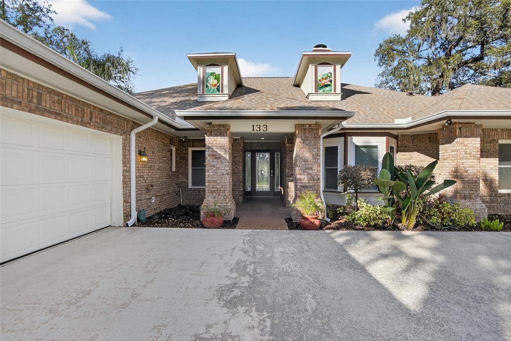 A brick house exterior features a front entrance, a garage, and two decorative dormer windows — 133 BARRINGTON DRIVE, BRANDON, FL