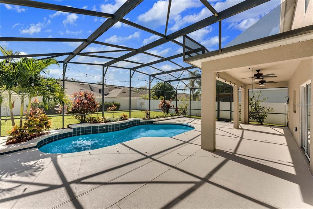 A screened-in patio features a swimming pool, a covered seating area, and tropical landscaping — 6309 EARTHGOLD DRIVE, WINDERMERE, FL