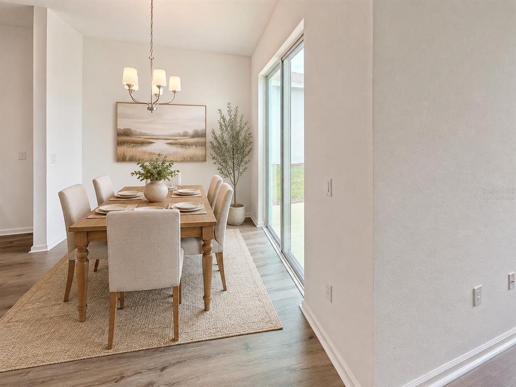 A dining room featuring a wooden table, six upholstered chairs, a chandelier, and sliding doors — 6213 SANDERS GROVE CIRCLE, LEESBURG, FL