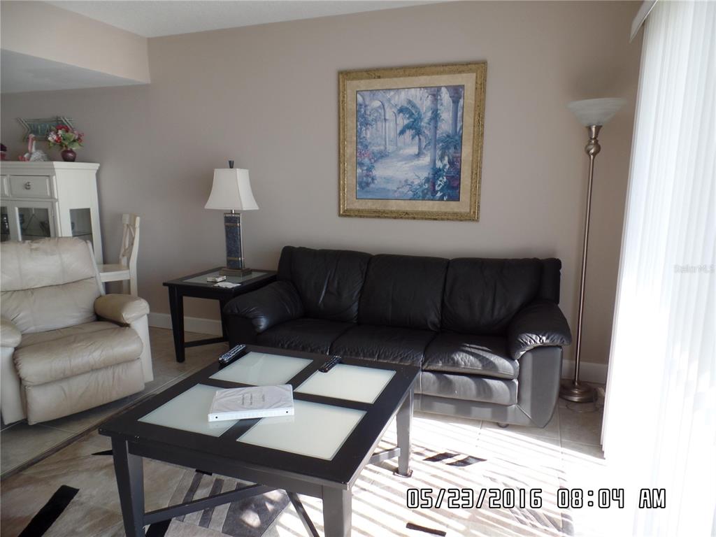 A living room features a black leather sofa, a glass-topped coffee table, and a recliner — 815 OCEAN SHORE BOULEVARD UNIT 13B, ORMOND BEACH, FL