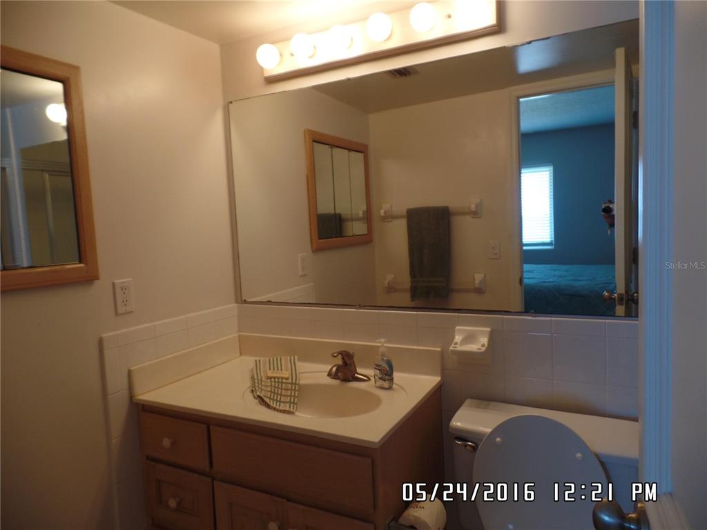 A bathroom features a wooden vanity with a sink, a large mirror, and a toilet — 815 OCEAN SHORE BOULEVARD UNIT 13B, ORMOND BEACH, FL