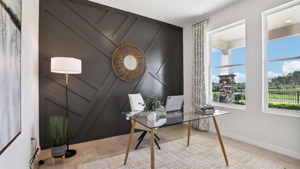 A home office features a dark accent wall with geometric trim, a glass desk, and windows — 2391 STERLING FOREST COURT, WESLEY CHAPEL, FL