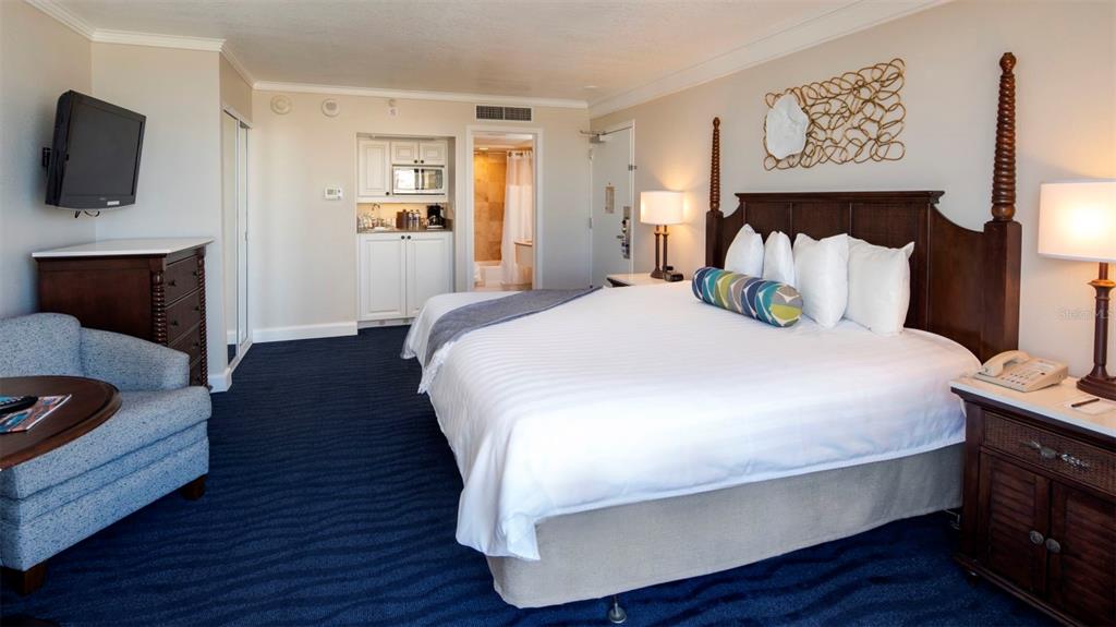A hotel room features a king bed, dark wood furniture, blue carpeting, and a kitchenette — 5500 GULF BOULEVARD UNIT 5227, ST PETE BEACH, FL
