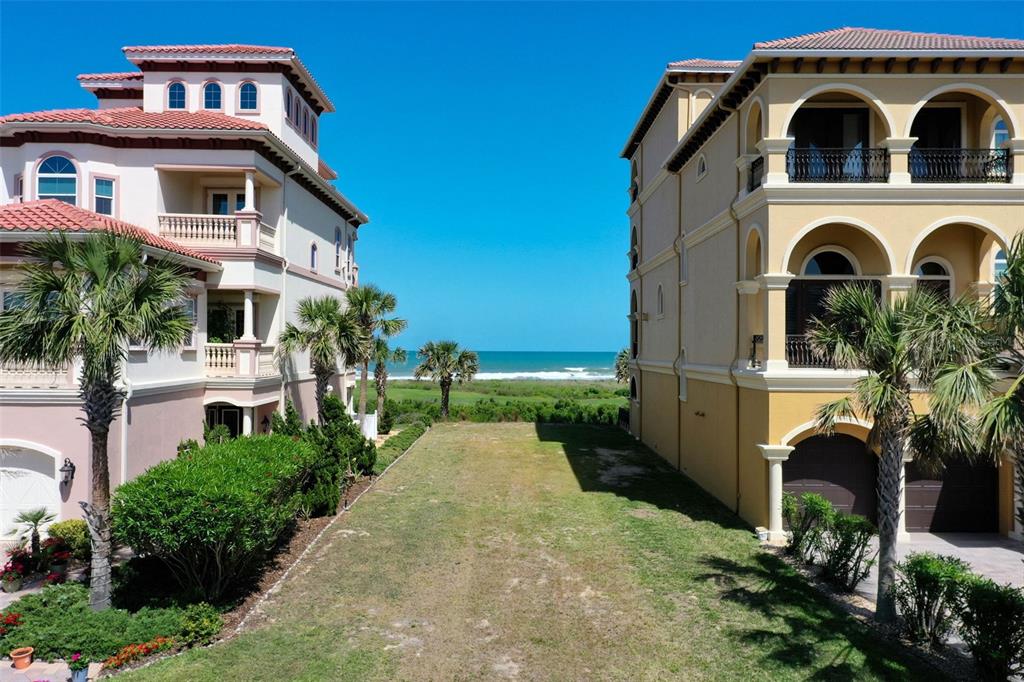 An empty grassy lot sits between two multi-story Mediterranean-style houses overlooking the ocean — 356 OCEAN CREST DRIVE, PALM COAST, FL
