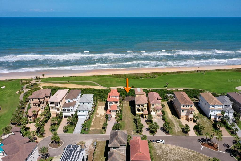 An aerial view shows a vacant oceanfront lot situated between two large residential homes — 356 OCEAN CREST DRIVE, PALM COAST, FL
