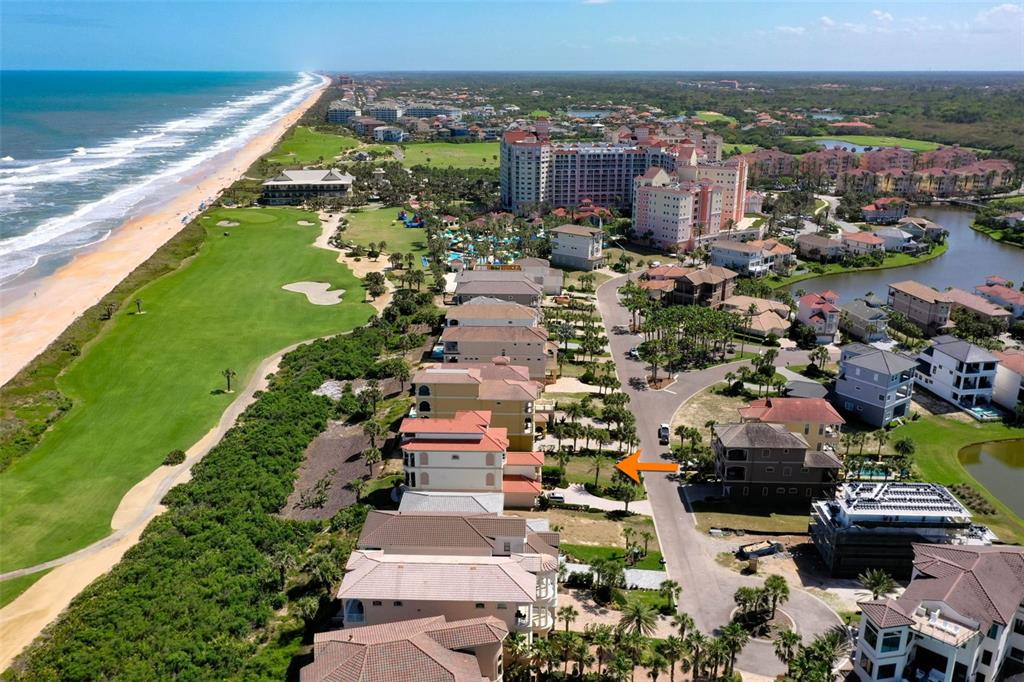 An aerial view shows a coastal neighborhood with a vacant lot marked by an orange arrow — 356 OCEAN CREST DRIVE, PALM COAST, FL